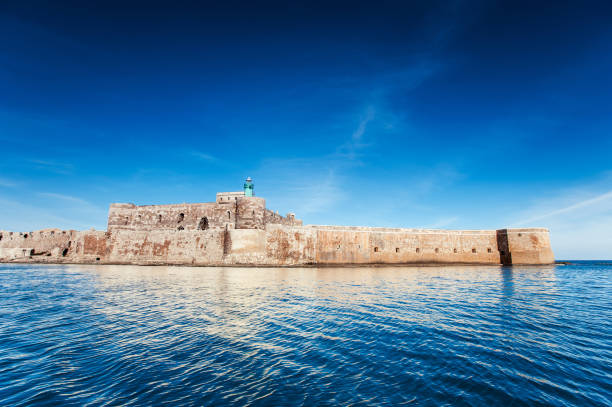 Panoramic Scenic view of Ortygia coastline and Castello Maniace castle on sea, Syracuse, Sicily, Italy. Summertime outdoors spectacular horizontal image with filter. Blue sky background