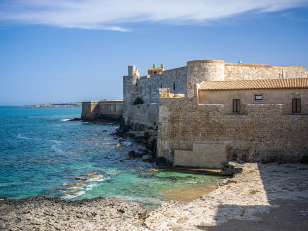 Castello Maniace Fortified Wall constructed between the year 1232 and 1240 towards the mediterranean sea on Ortygia Island at the old town of Syracuse City. Medieval Old Town City Wall at the Eastern Coast of Sicily Island towards the Mediterranean Sea under blue summer sky. 102 MPixel Hasselblad X2D Architecture Shot. Maniace Fortress, Castello Maniace , Syracuse, Ortygia Island, Sicily, Italy, Southern Europe